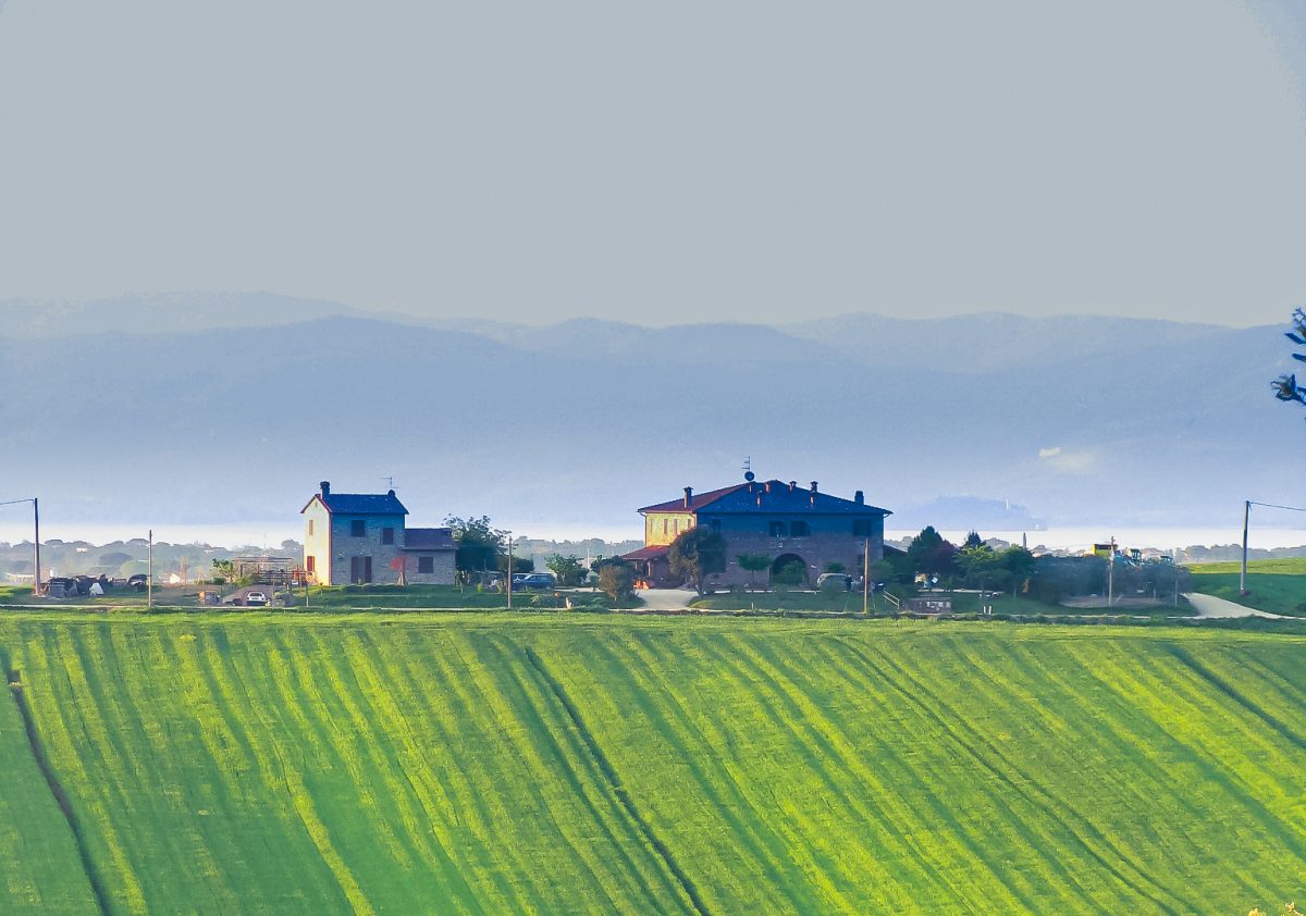 Tenuta Badia farmhouses among green fields and distant hills