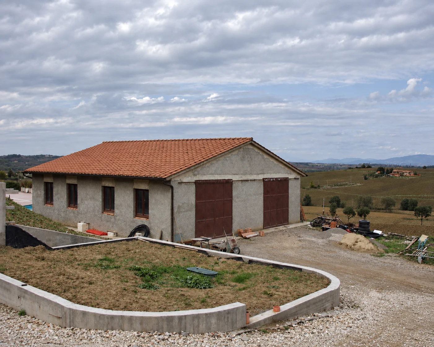 Foto storica del capannone della Tenuta Badia a Paciano, con tetto in cotto, portoni scuri e terreno in primo piano