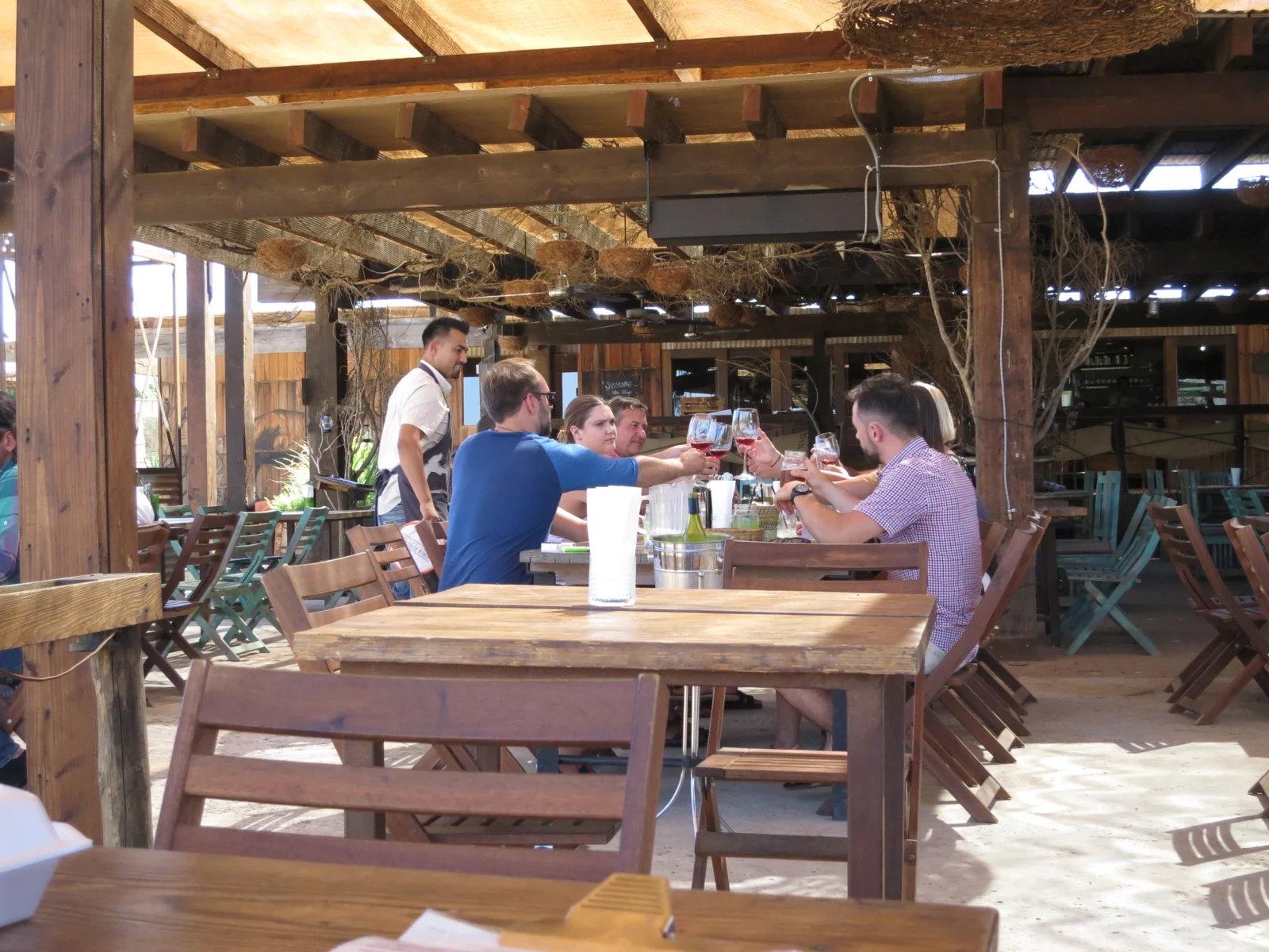 Amici che brindano con calici di vino a un tavolo sotto una veranda in legno; foto illustrativa