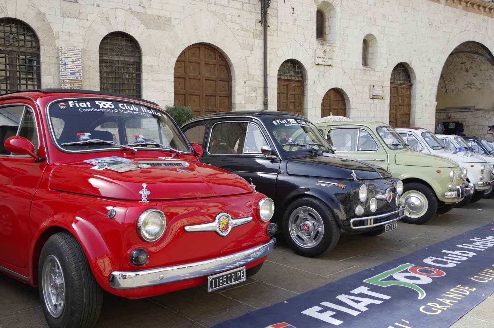 Fiat 500 storiche rosse, nere e chiare schierate durante un raduno ad Assisi