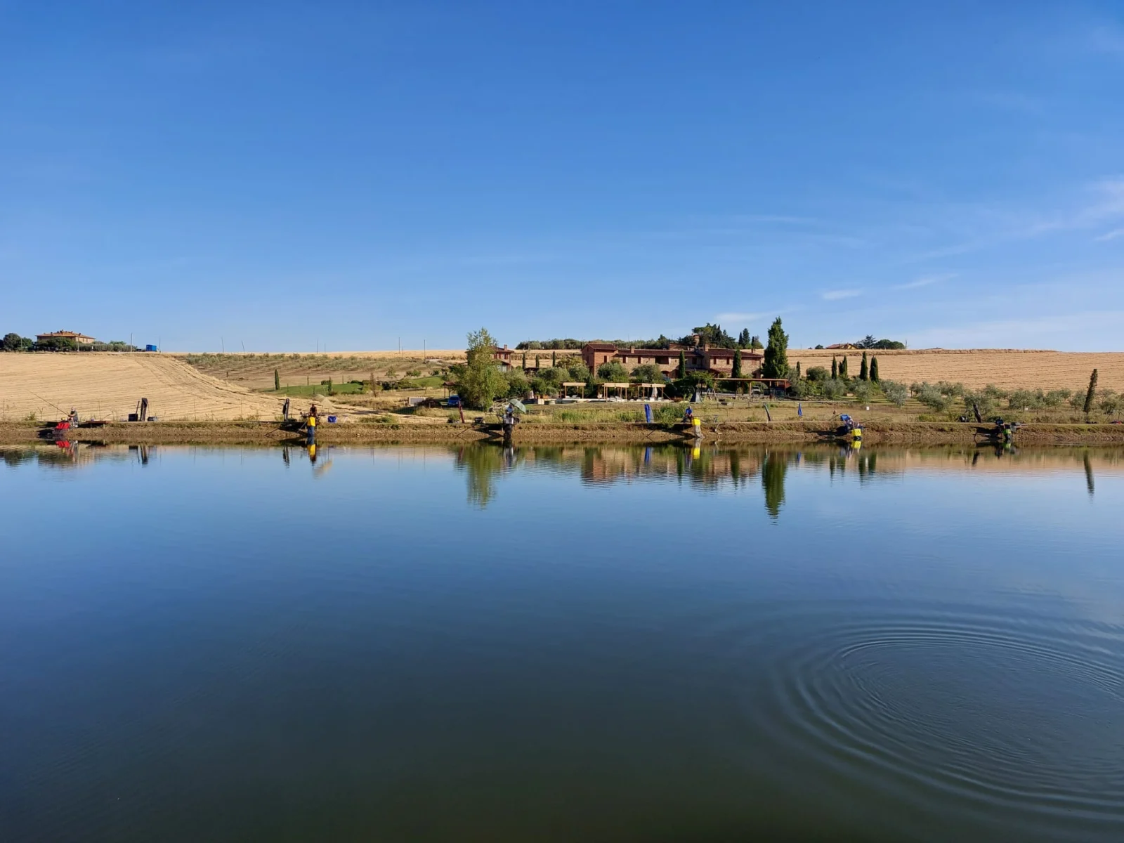 Lago della Fishing Accademy a Paciano con pescatori sulla sponda e campagna sullo sfondo