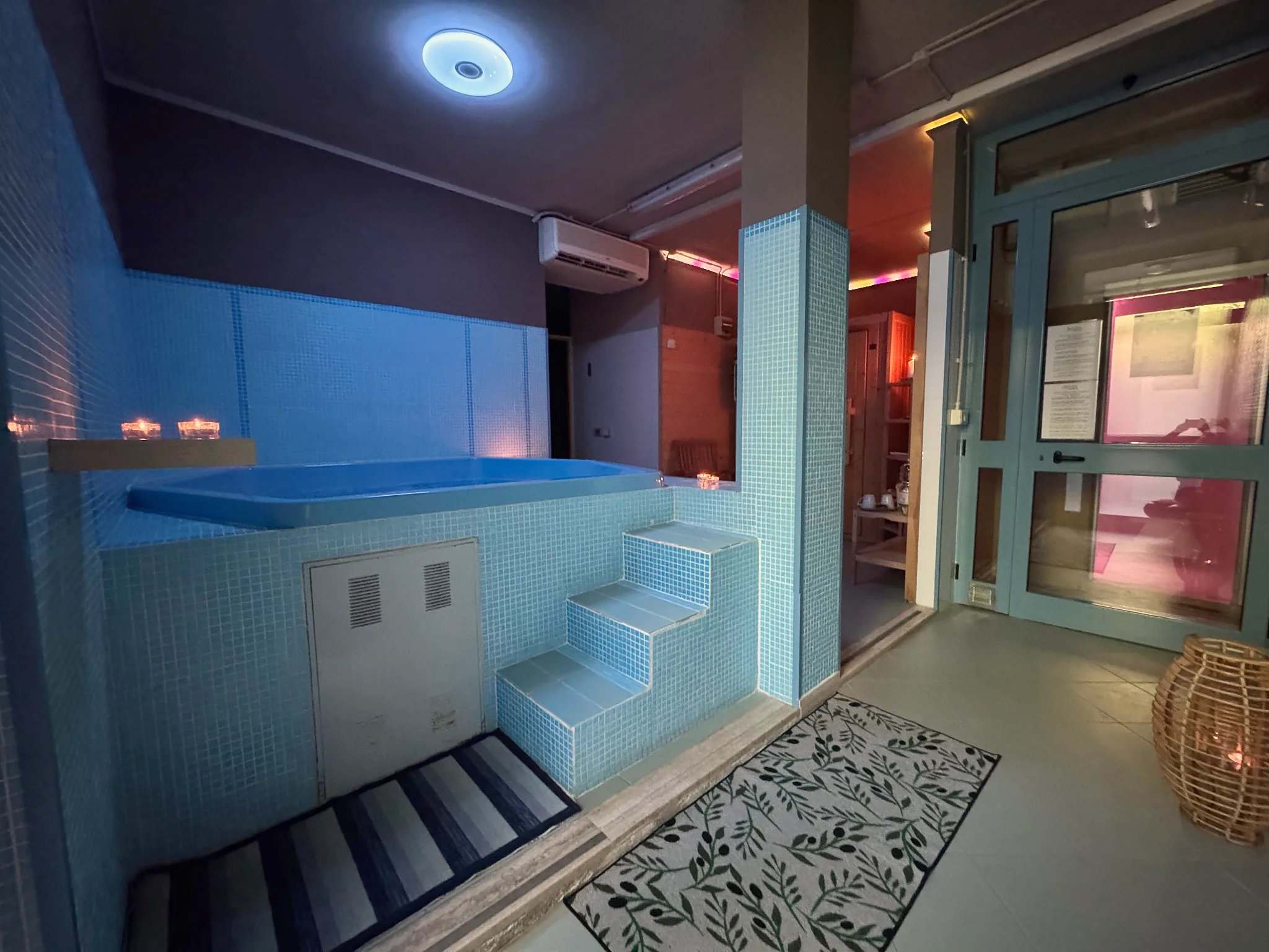 Blue mosaic spa pool with steps and soft lighting in the wellness area of Tenuta Badia.