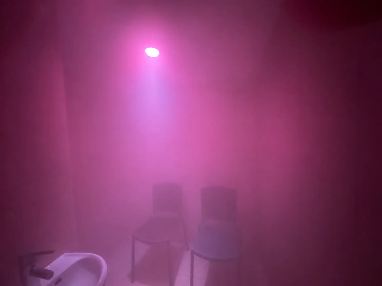 Ambiente con vapore, due sedute e illuminazione rosa nella SPA di Tenuta Badia