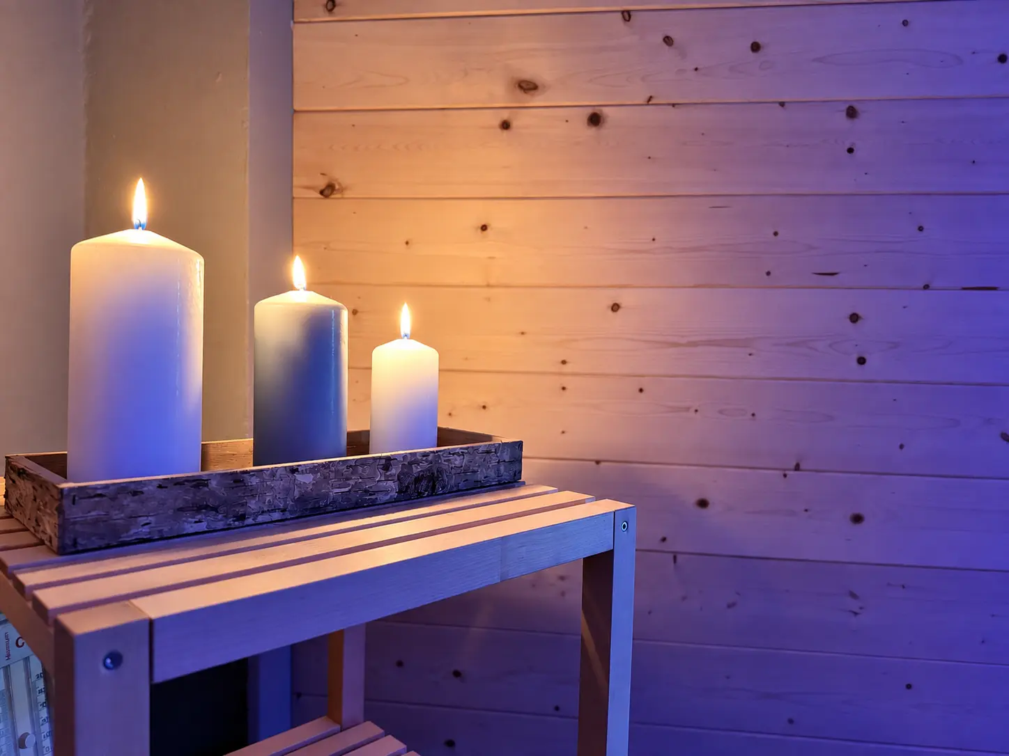 Tre candele accese su una mensola in legno nella SPA di Tenuta Badia